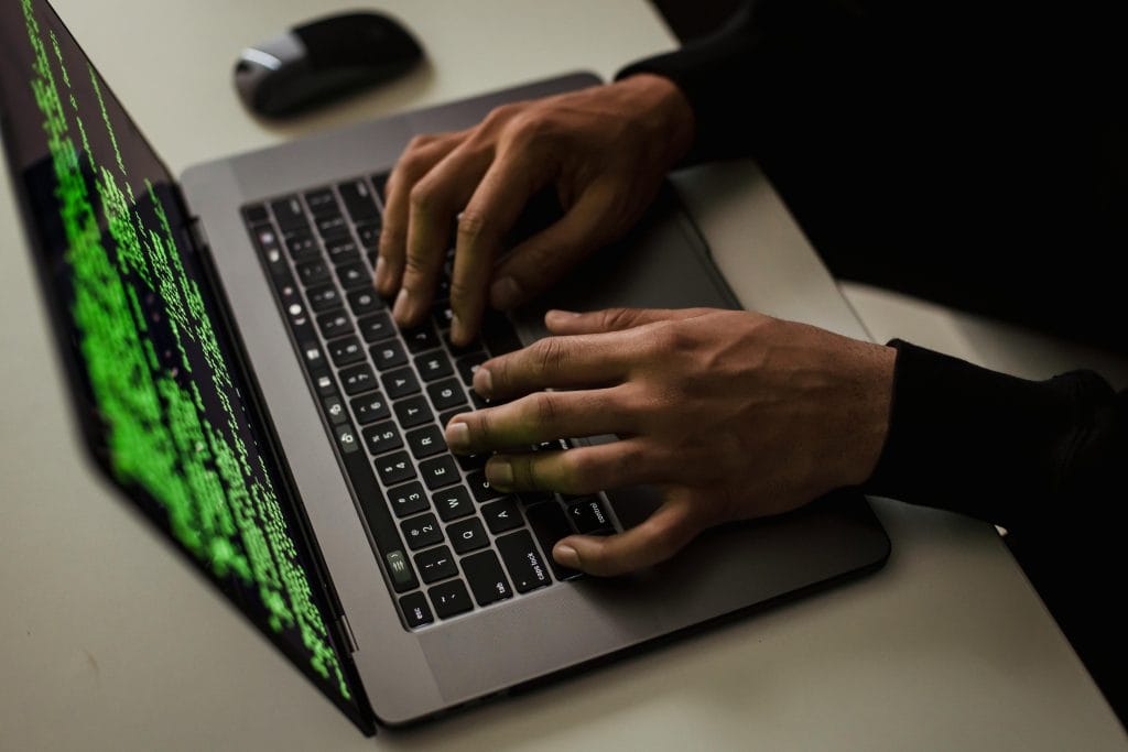 Mains utilisant un ordinateur dans un environnement évoquant la protection des données numériques